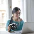 woman holding a camera sitting in front of laptop