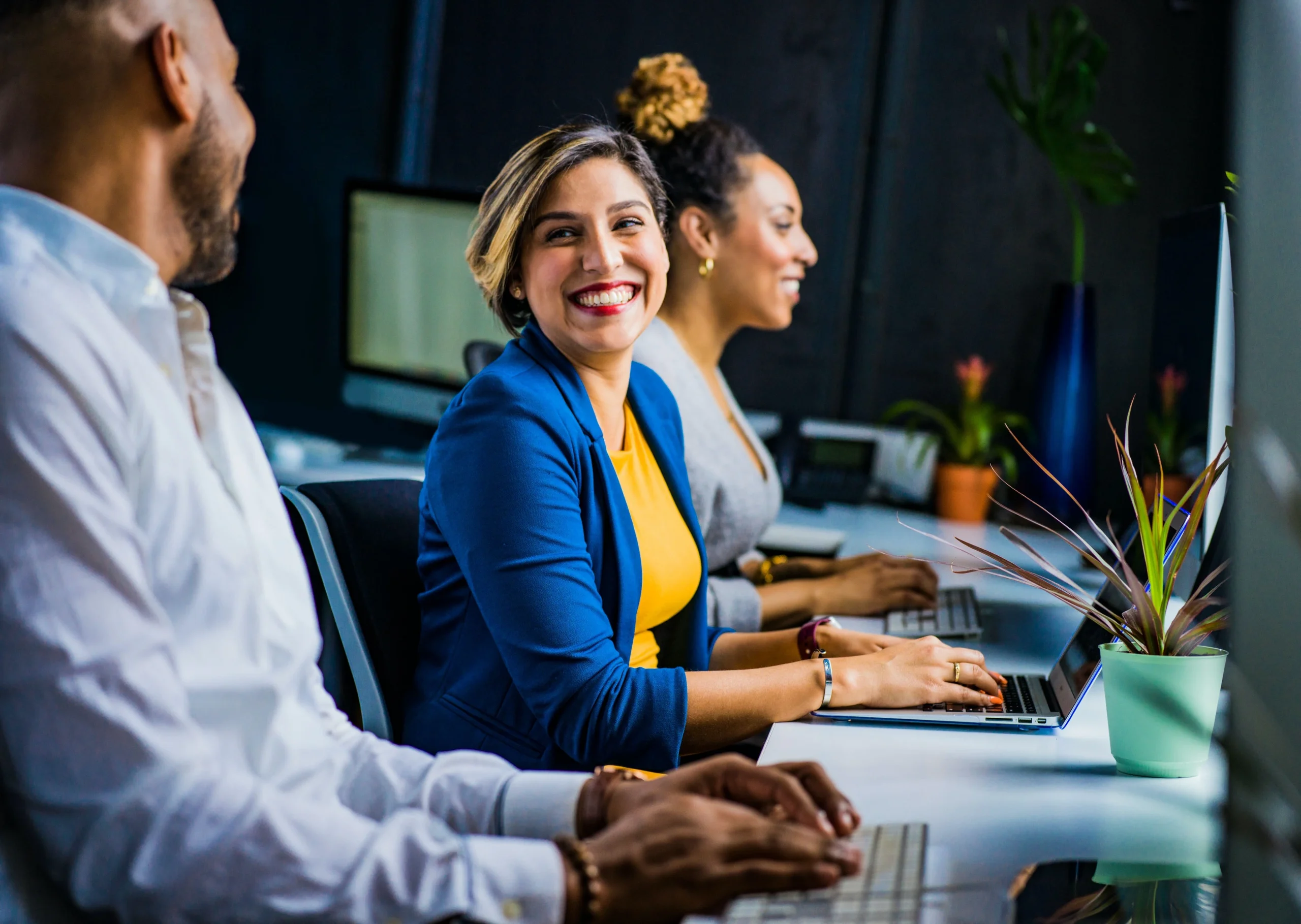 smiling employees working with laptops